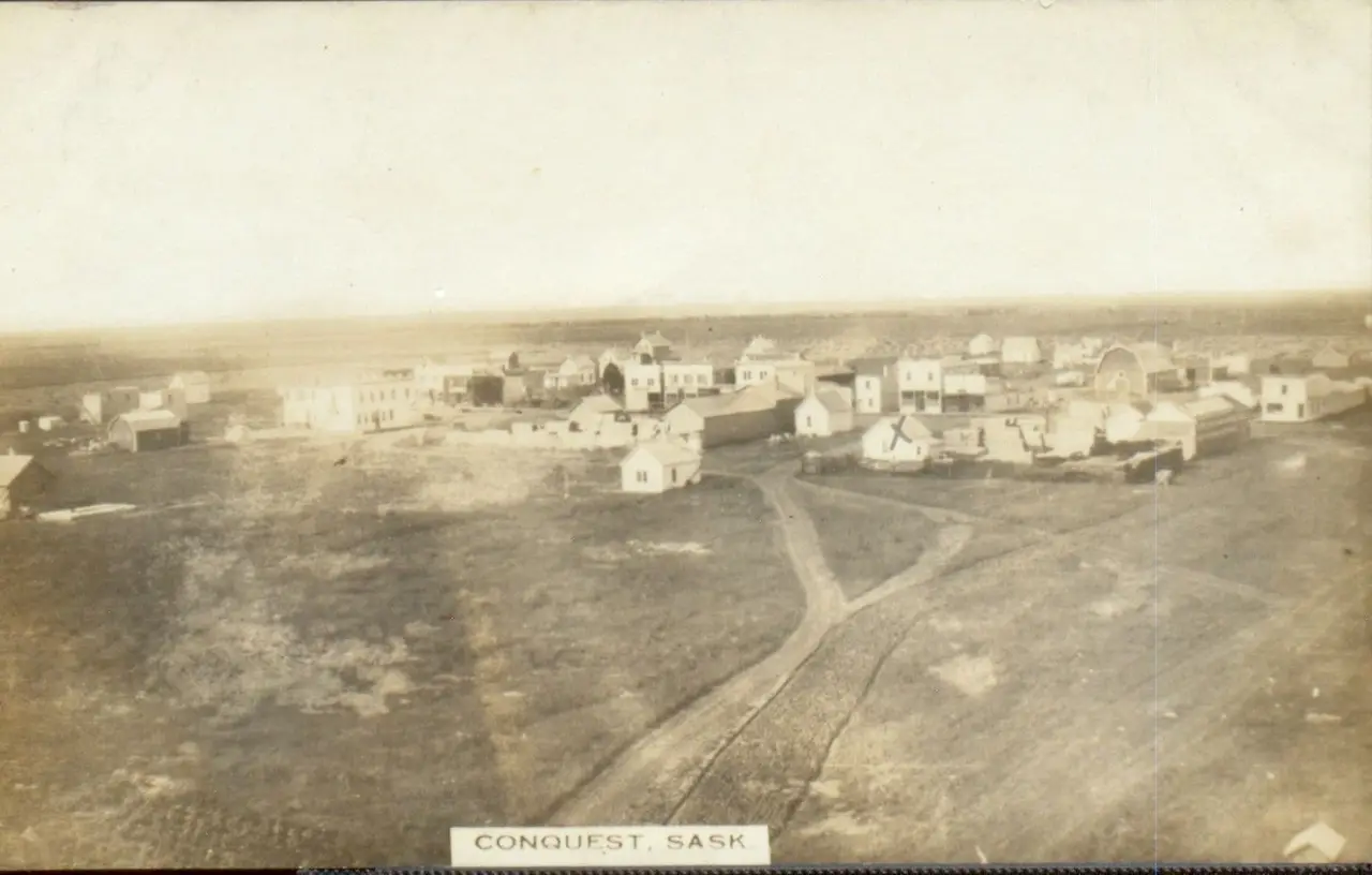 Aerial view of Conquest from a height, with dirt roads leading into town, about 1912